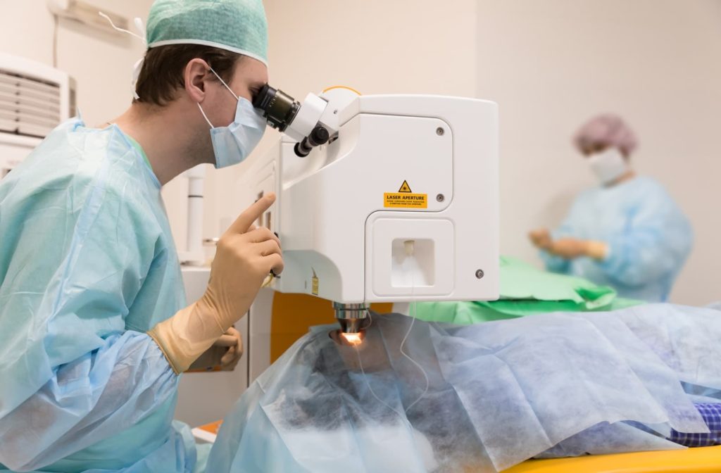 Ophthalmologist performing laser eye surgery while the patient is laying down and covered with a blue blanket