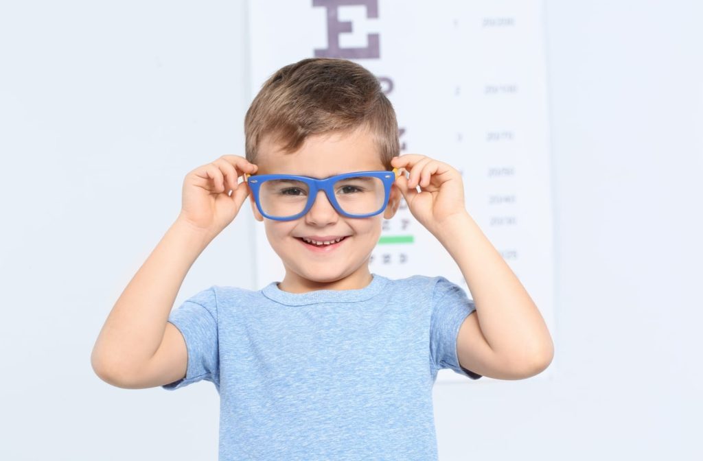 Little boy with blue glasses visiting the optometrist to choose the best glasses for him