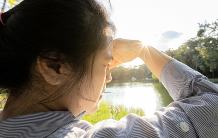 An over the shoulder view of a woman trying to block her eyes from the sun