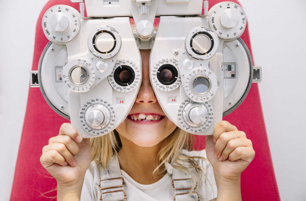 A young girl looking through a phoropter during a kids eye exam