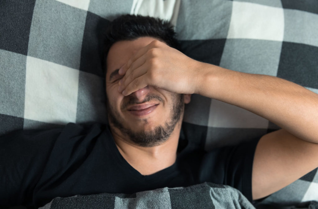 Man in discomfort rubbing his eyes after waking up