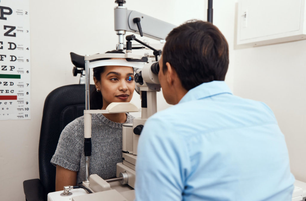 An optometrist performing an eye examination on a woman using a specialized medical device to check for any eye problems.