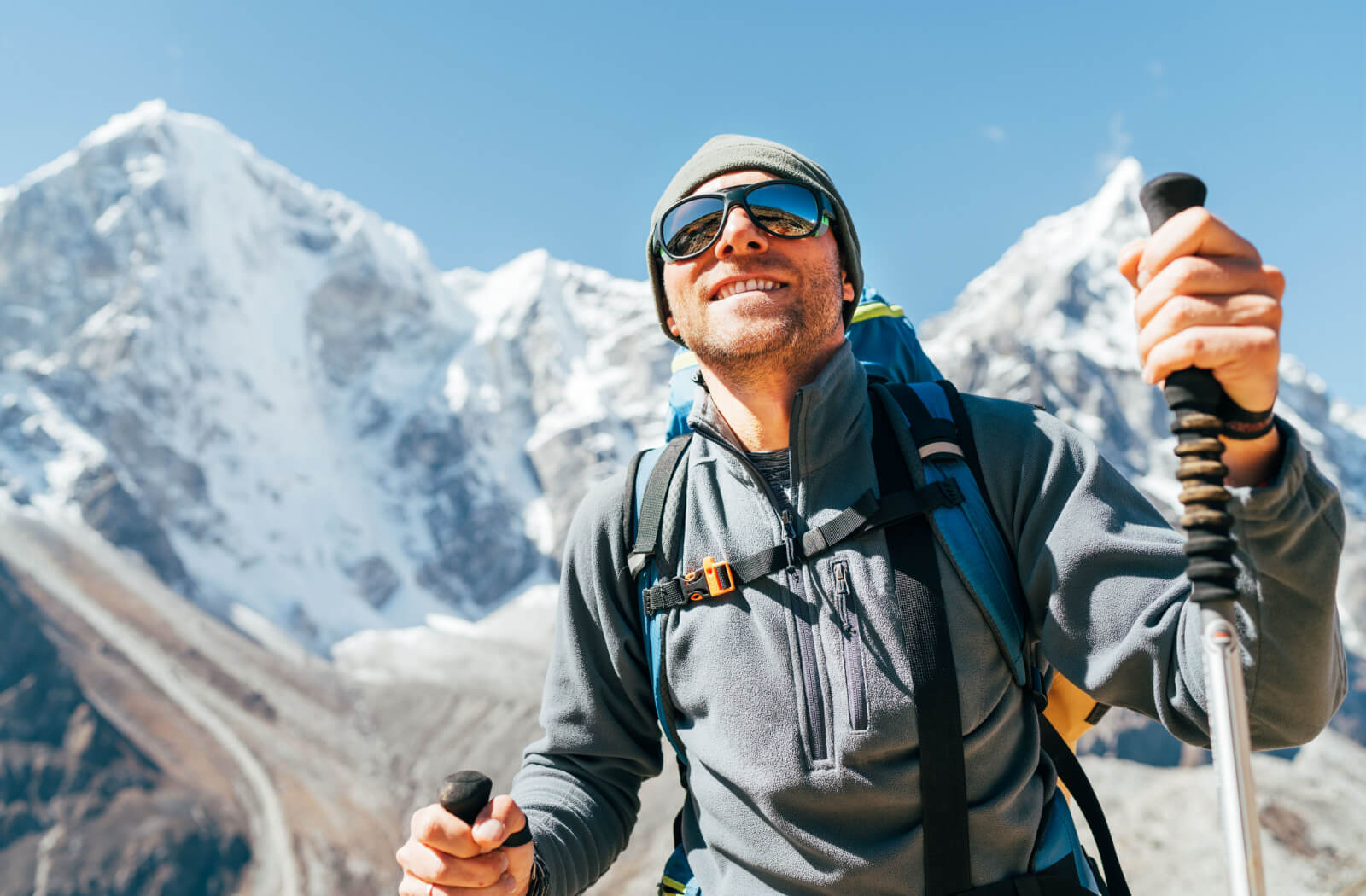 A man outside hiking a mountain while wearing UV protection sunglasses to protect his eyes.