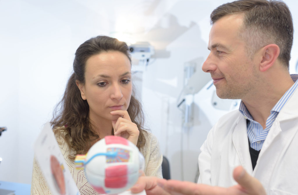 An optometrist explaining the procedure to her patient using a 3D model of an eye.