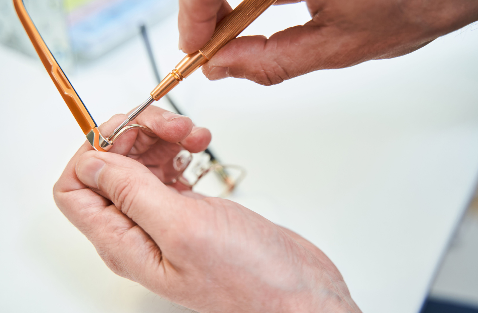 The man's hands grip a screwdriver as he skillfully tightens the eyeglass temple, ensuring a secure and comfortable fit for the wearer.