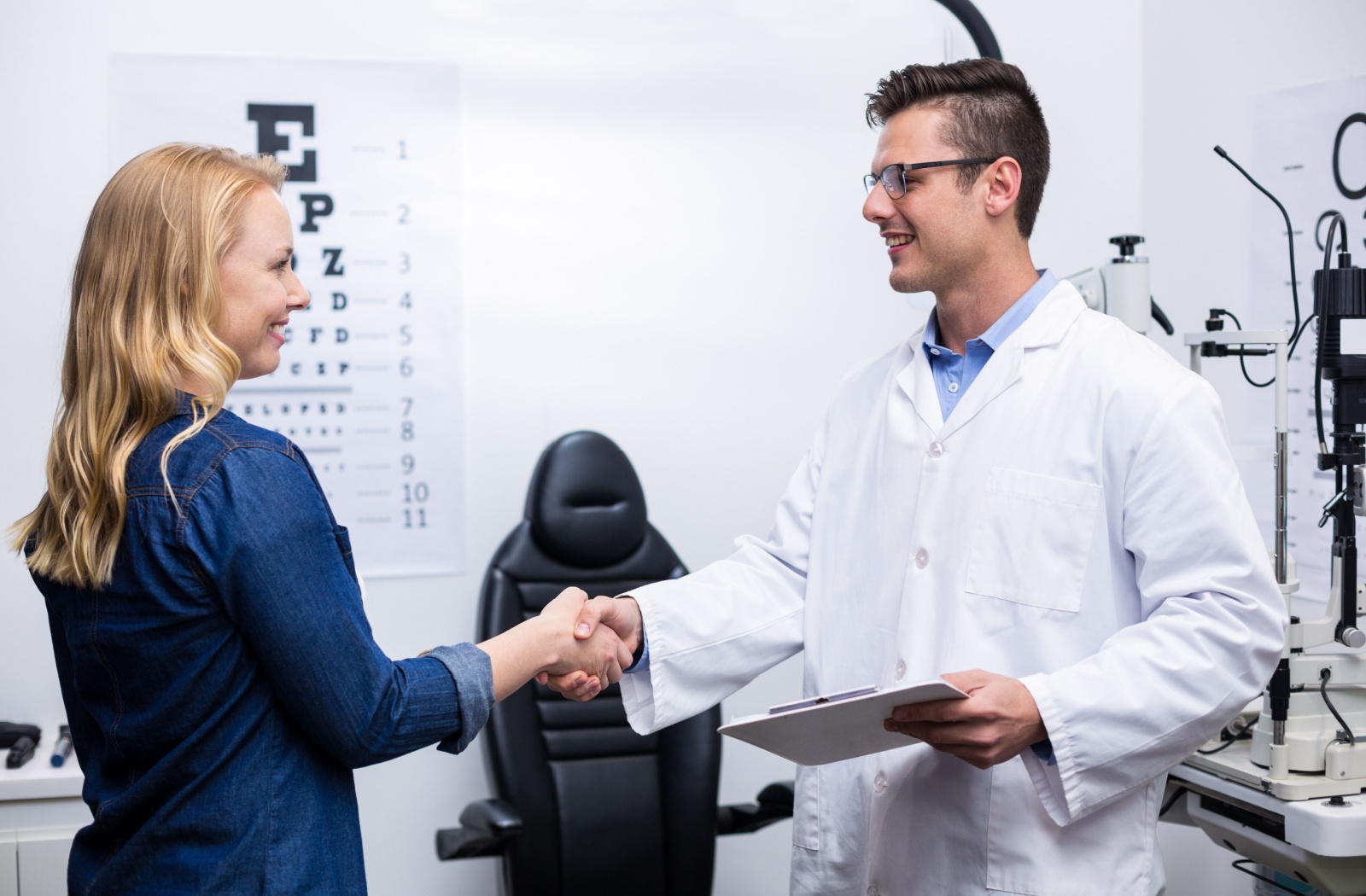A woman in an optometry clinic shaking hands with her male optometrist
