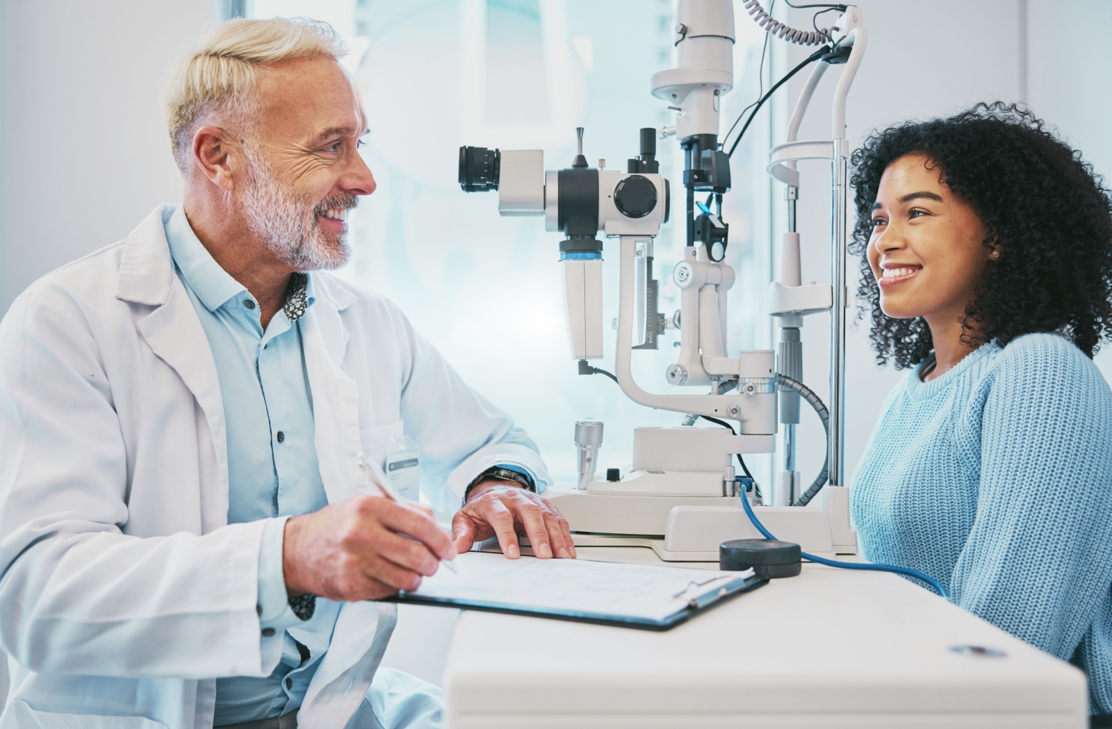 An optometrist sits across from his patient and discusses their eye exam results