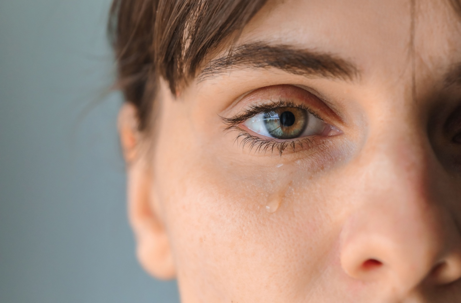 A close-up of a patient with a tear rolling down their face.