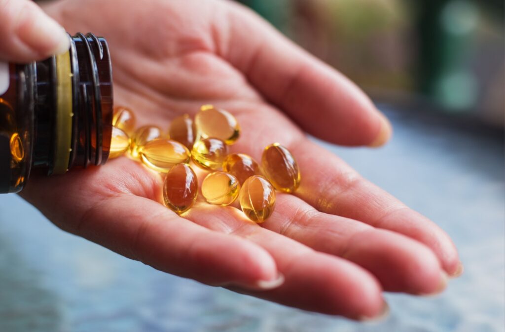 A hand pouring omega 3 supplements into it.