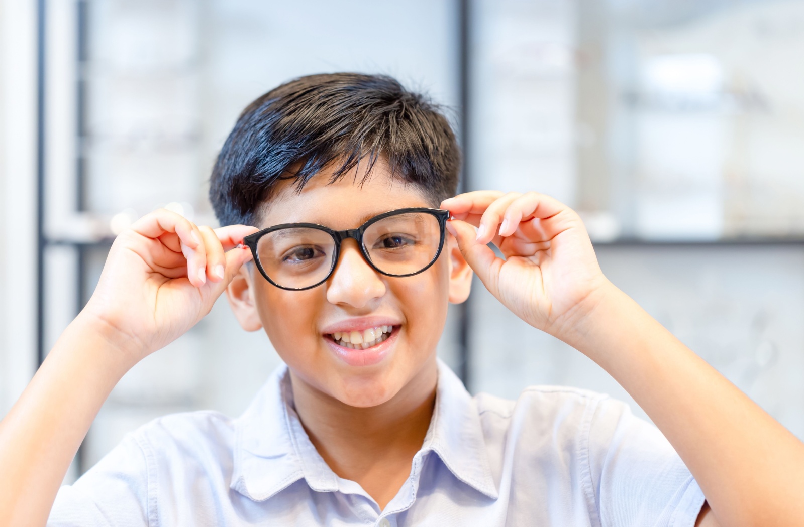Kid smiling while wearing a pair of glasses