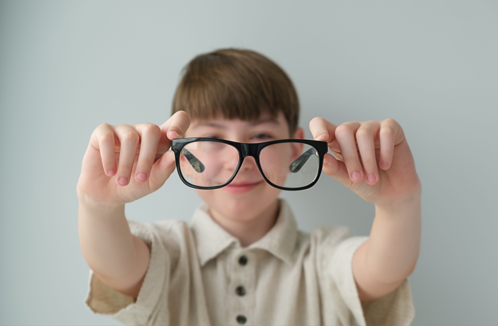 A smiling child holds out their new pair of glasses.