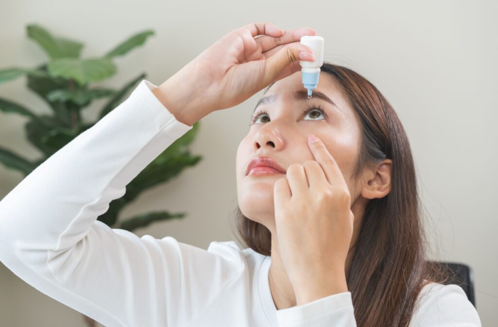 A person pulling their skin under their eye down while they look up to put eye drops in their eye